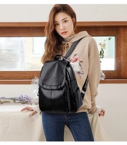 Detail of black leather backpack featuring kangaroo embossed logo and side pocket texture