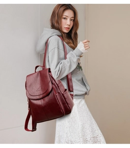 Side view of a burgundy leather backpack with a flap cover and kangaroo logo engraving