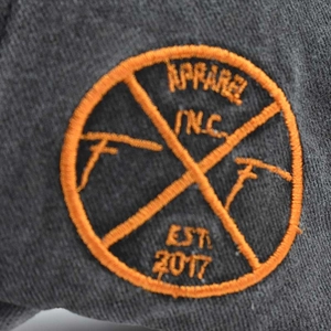 Detail of orange embroidery on grey vintage baseball cap with 2017 apparel badge