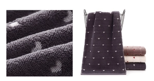 Macro detail of plush heart pattern towels in purple and beige on a storage basket