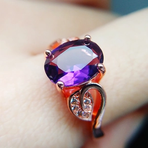 Macro view of rose gold leaf ring with oval purple gemstone and crystal accents