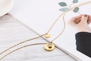 Macro detail of gold double-layer necklace with heart and engraved circular pendants