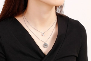 Detail of silver double layer necklace featuring an engraved heart pendant on a model