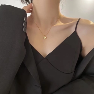Elegant 18K gold heart necklace with white shell pendant worn by a model in a suit