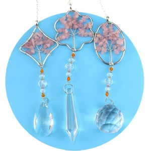 Three handmade rose quartz tree of life pendants with hanging crystal prisms on blue background