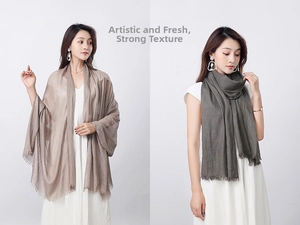 Detail of light brown and dark grey linen scarves featuring natural tassel edge and soft texture