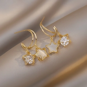Elegant gold double star drop earrings with cubic zirconia on a luxury silk background