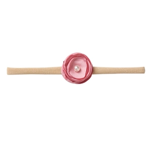 Detail of pink fabric flower with faux pearl on beige elastic nylon baby headband