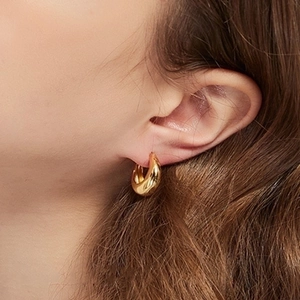 Polished gold chunky drop earrings for women with high gloss finish on female model