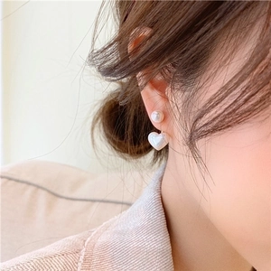 Close-up of elegant pearl heart drop earrings worn on a model for a luxury look