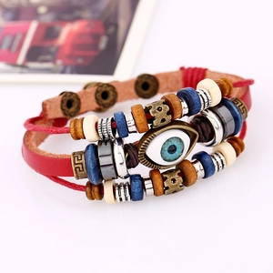 Macro shot of evil eye charm on multilayer red leather and braided beaded bracelet