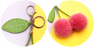 Macro detail of plush cherry keychain with pink pom-poms and golden lobster clasp hardware