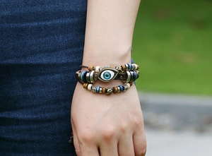 Close-up of a layered leather beaded bracelet with blue eye charm on a model wrist