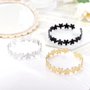 Three minimalist daisy pattern open rings in gold, silver, and black finish on a magazine