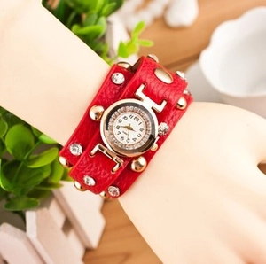 Dettaglio cinturino in pelle PU rossa con borchie dorate e cristalli su orologio