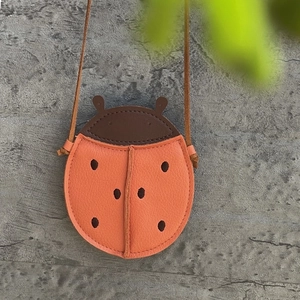 Detail view of ladybug-shaped kids leather bag with litchi texture and orange finish