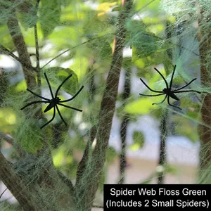 Detailed view of green spider web cotton with two small plastic spiders on tree branches