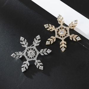 Close-up of gold and silver snowflake brooches with crystals on black and white paper