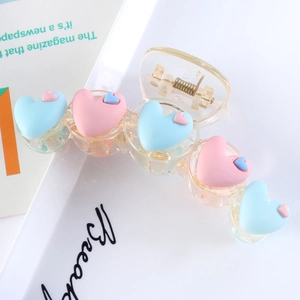 Detail of transparent acrylic hair claw featuring colorful matte resin heart decorations