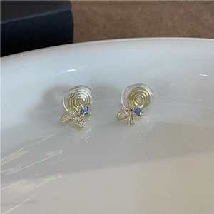 Macro detail of gold clip-on earring with blue and white zircon star pattern