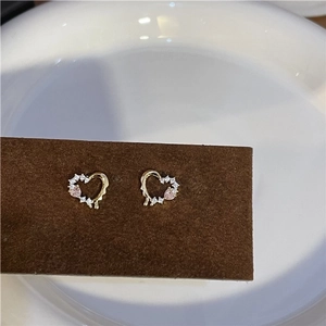 Macro detail of heart earrings with pink teardrop stones and white zircons on velvet