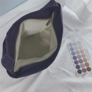 Detailed top view of purple canvas bag showing cream lining and sturdy metal zipper