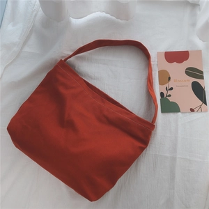 Macro shot of burnt orange canvas bag with visible white contrast stitching and wide strap