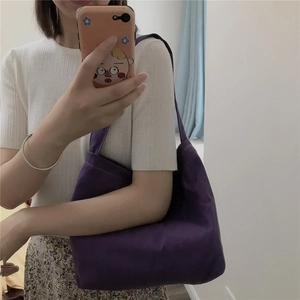 Detailed side view of a purple canvas tote bag worn as a shoulder bag for daily use