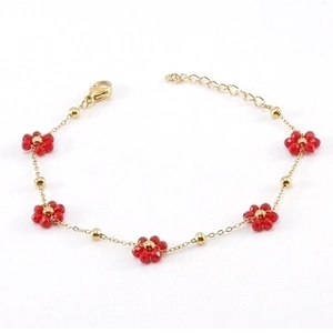 Elegant gold chain bracelet with red crystal flowers on a clean white background