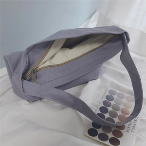 Detail of light purple canvas underarm bag with metal zipper and wide strap