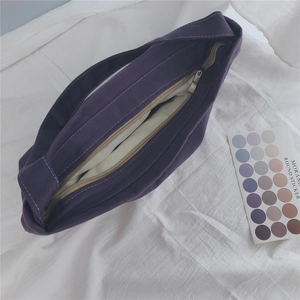 Top view of purple canvas shoulder bag showing white lining and metal zipper closure