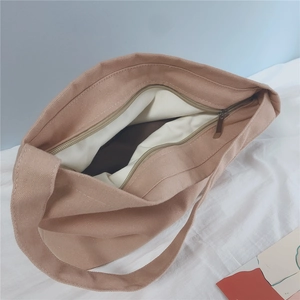 Detailed close-up of the metal zipper closure and inner lining of this beige canvas bag