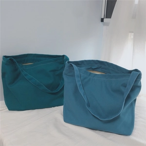 Detail of dark teal and grey blue canvas shoulder bags with zipper and wide straps