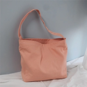 Detail of light coral canvas tote bag with shoulder strap on white fabric surface