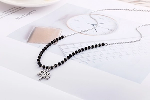 Detail of silver chain with black faceted beads and hollow Tree of Life pendant charm