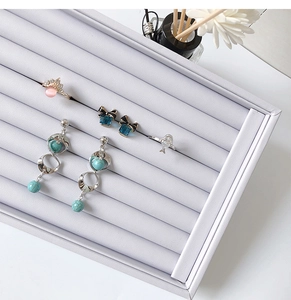 Macro shot of assorted gemstone rings and earrings arranged in a soft velvet display tray