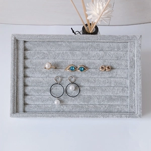 Gray velvet jewelry display tray with multiple slots for rings and earrings storage