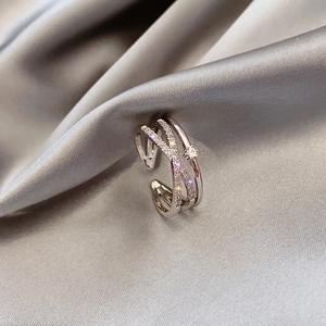 Close-up of double-layer crisscross silver ring with zircons on gray silk fabric