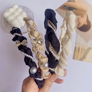 Elegant woven headband with faux pearls and rhinestones shown in a hand-held close-up