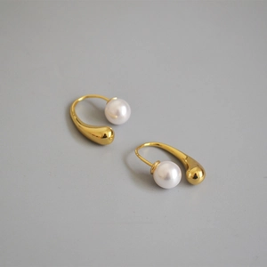 Detail of elegant gold-plated drop earrings featuring teardrop design and white pearls