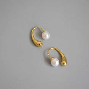 Elegant gold teardrop earrings with white pearls on a neutral background