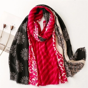 Detail of floral printed scarf with pink stripes and fringe edges on a white background