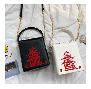 Detail view of black and white PU crossbody bags with red pagoda print and gold chains