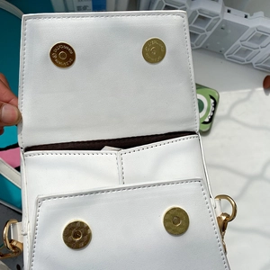 Detailed view of white PU crossbody bag featuring dual golden magnetic snap closures