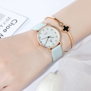 Close-up of light blue leather strap watch and lucky clover bracelet on woman's wrist