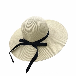 Dettaglio cappello di paglia a tesa larga bianco con nastro nero e fiocco chic