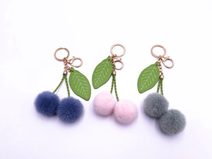 Detailed close-up of plush cherry keychains in navy blue, light pink, and grey colors