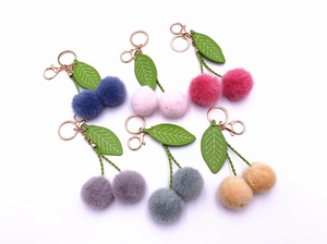 Close-up of cherry plush ball keychains in multiple colors with gold spring clasps