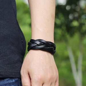 Classic black braided leather bracelet for men shown on a wrist with natural outdoor lighting