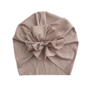 Detail of baby turban hat showing ribbed knit fabric texture and large fabric flower
